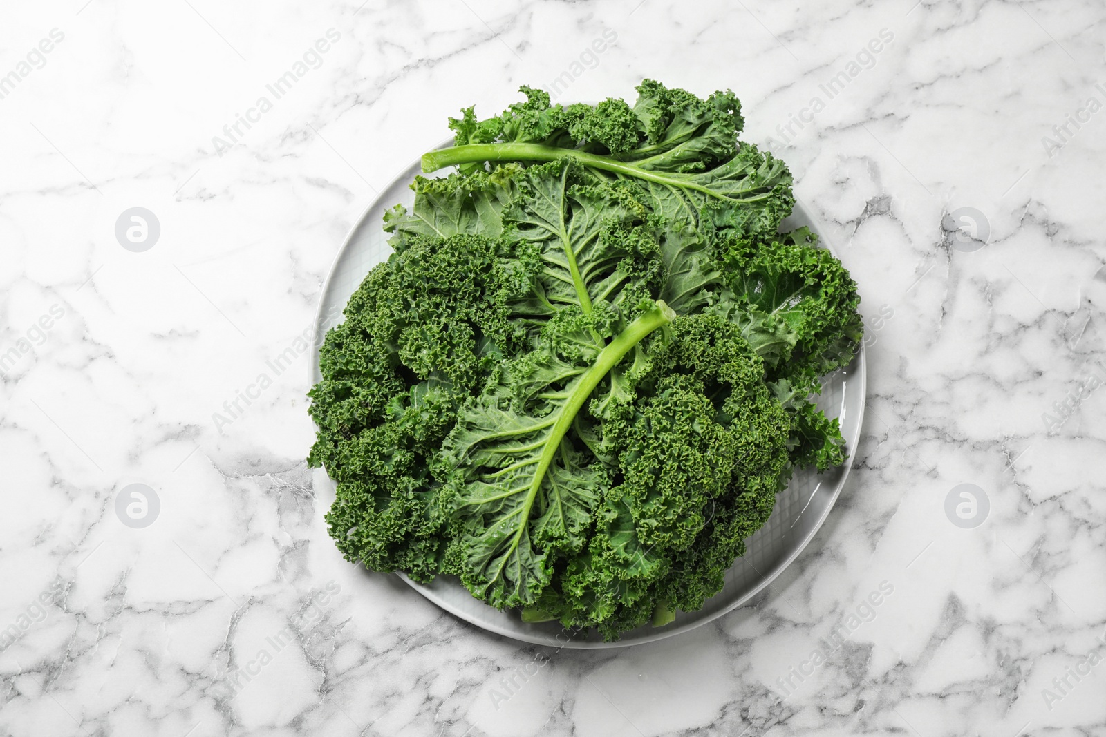 Photo of Fresh kale leaves on white marble table, top view