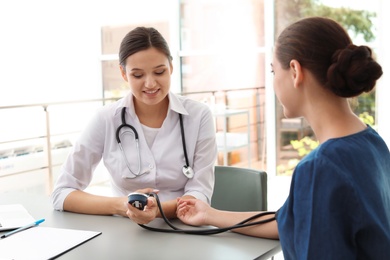 Doctor checking patient's blood pressure in hospital