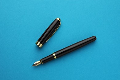 Photo of Stylish fountain pen with cap on light blue background, flat lay