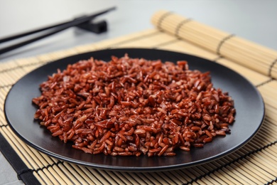 Plate with delicious cooked brown rice on table