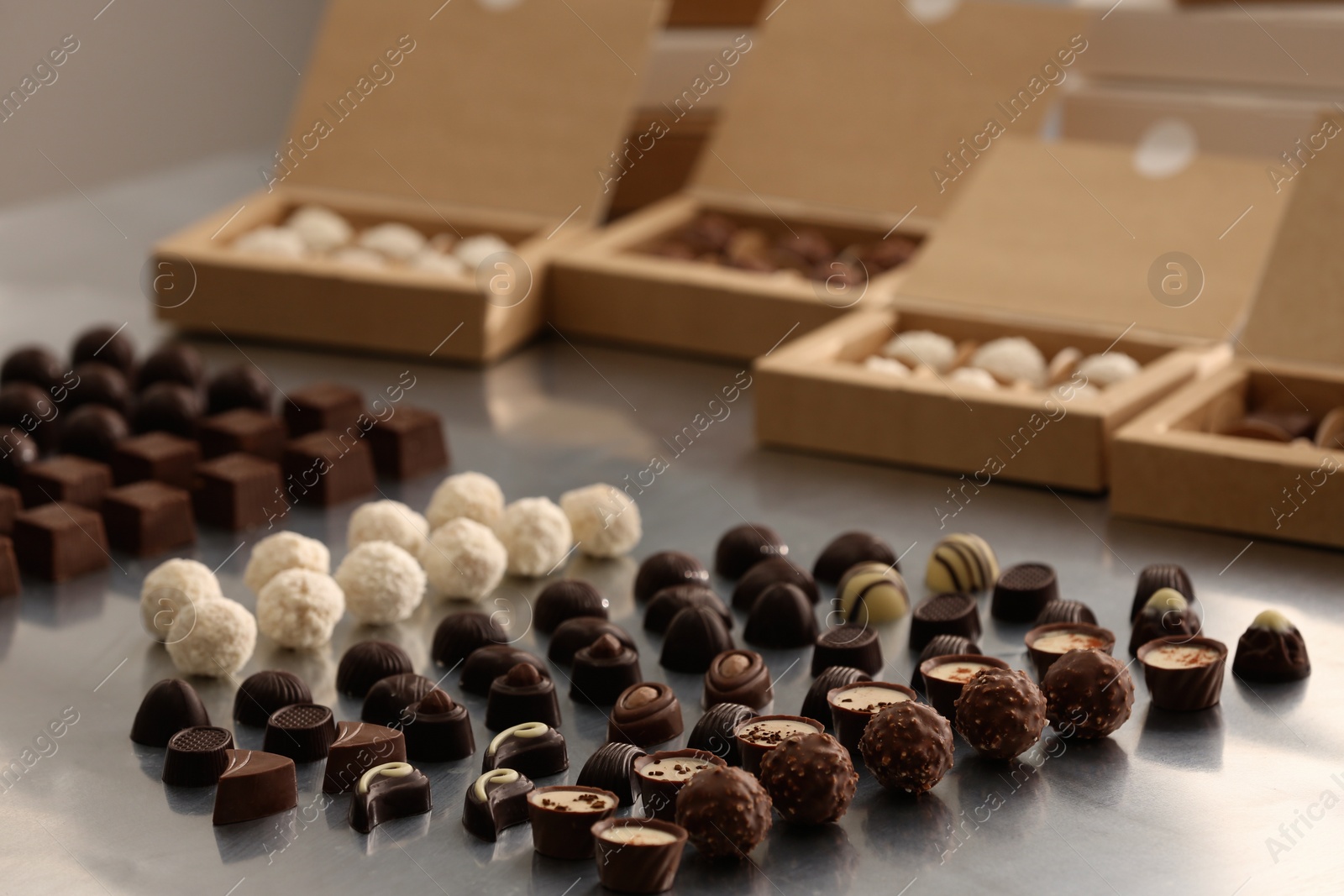 Photo of Different delicious chocolate candies and boxes on white table. Production line