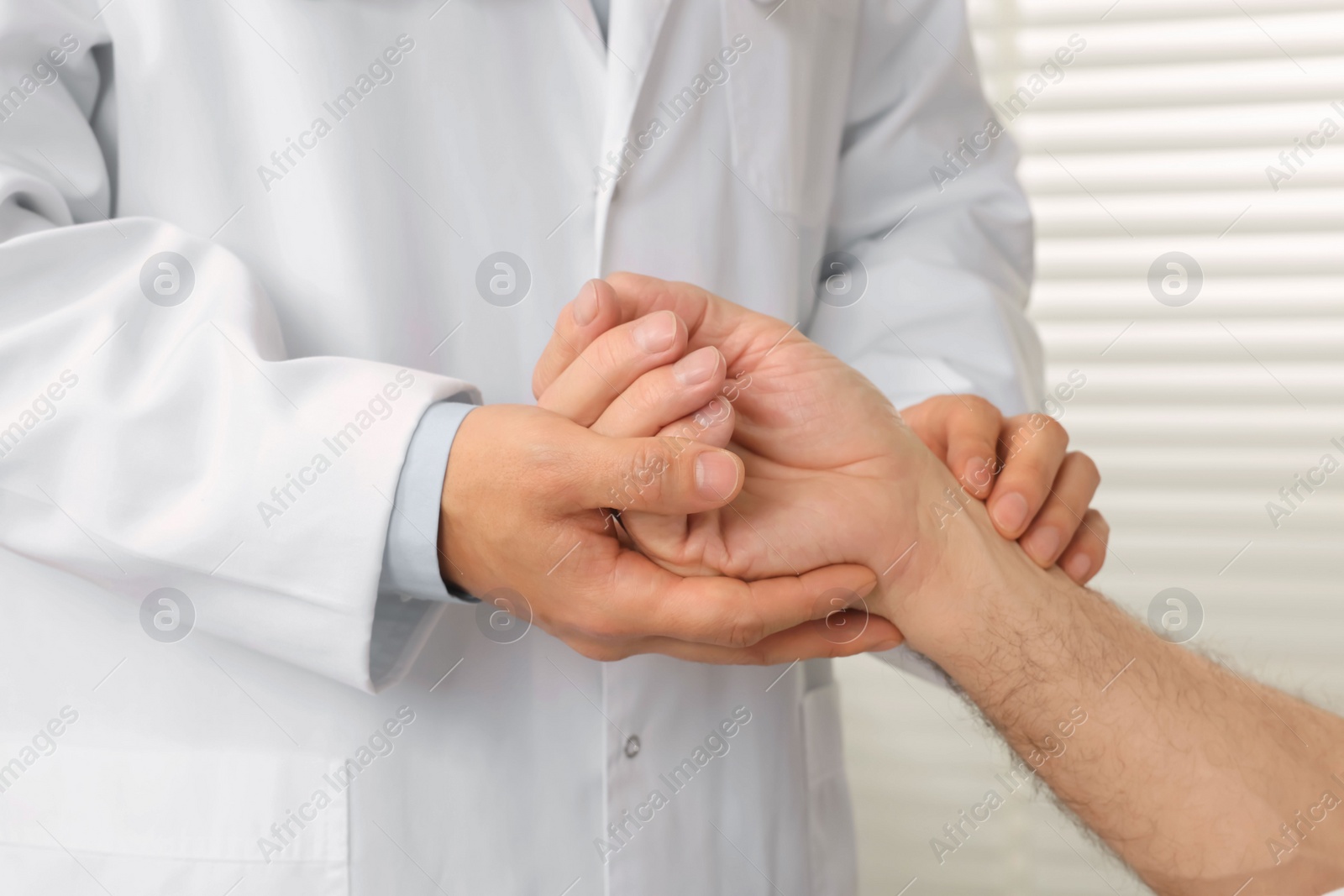 Photo of Doctor checking senior man`s pulse in hospital, closeup