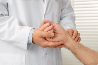 Doctor checking senior man`s pulse in hospital, closeup