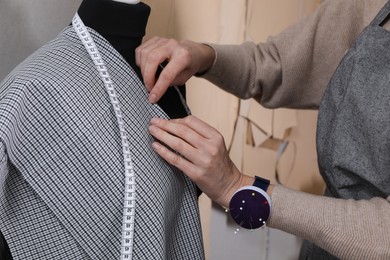 Tailor pinning fabric at mannequin in atelier, closeup