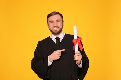 Happy student with diploma on yellow background