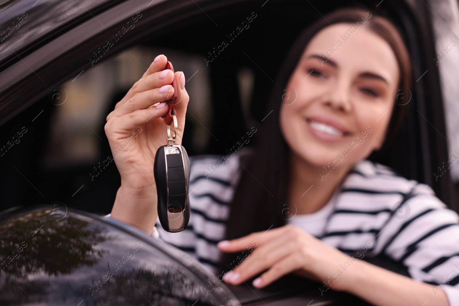 Photo of Woman holding car flip key inside her vehicle, selective focus