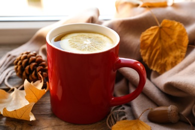 Cup of hot drink, scarf and autumn leaves on windowsill. Cozy atmosphere