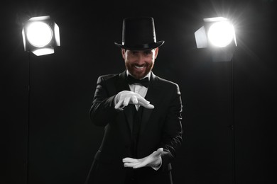 Photo of Happy magician in top hat holding something on stage