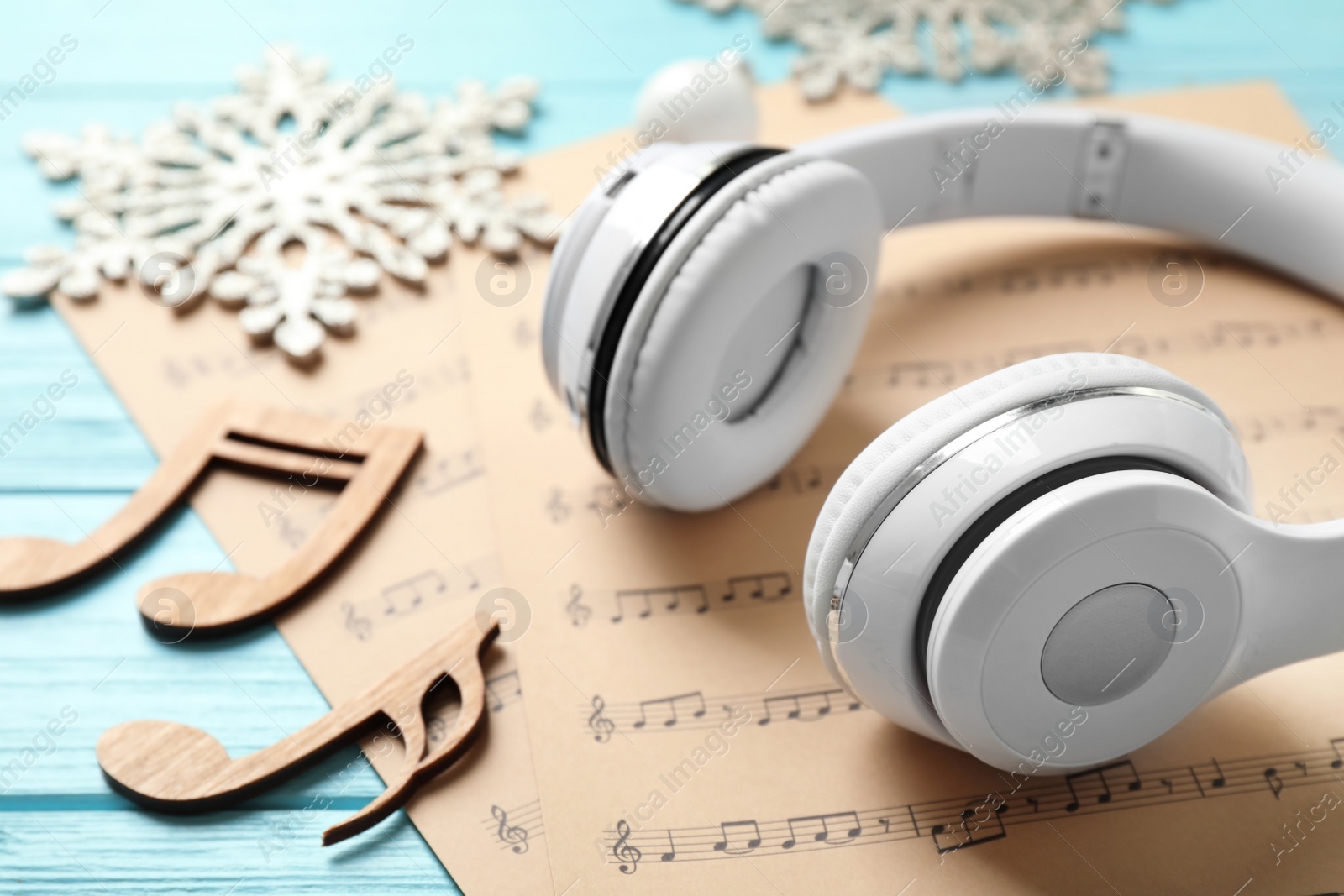 Photo of Christmas decorations, headphones and music sheets on blue wooden table, closeup
