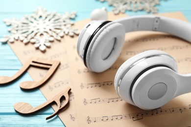 Christmas decorations, headphones and music sheets on blue wooden table, closeup