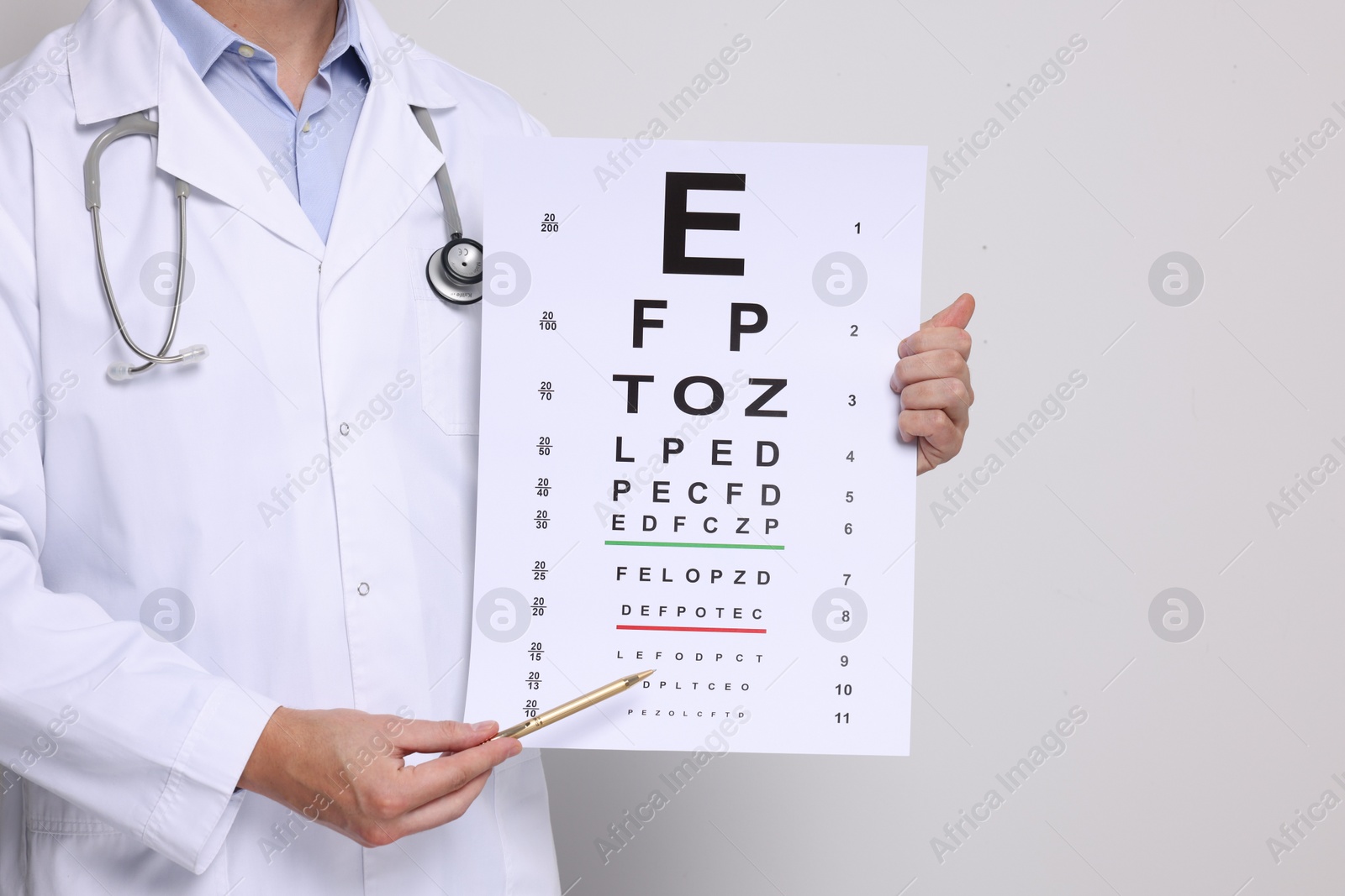 Photo of Ophthalmologist pointing at vision test chart on light background, closeup
