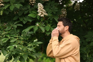 Man suffering from seasonal spring allergy near tree in park