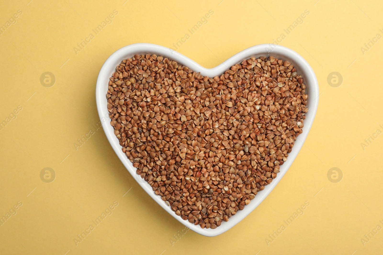 Photo of Buckwheat grains on light yellow background, top view