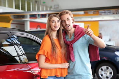 Photo of Happy young man and woman in modern car dealership