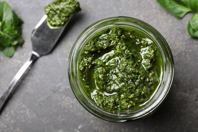 Photo of Homemade basil pesto sauce in glass jar on table, top view