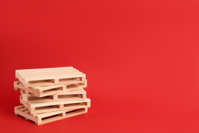 Photo of Stack of wooden pallets on red background, space for text