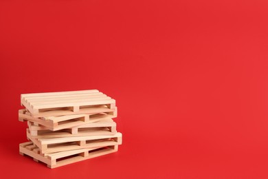 Stack of wooden pallets on red background, space for text