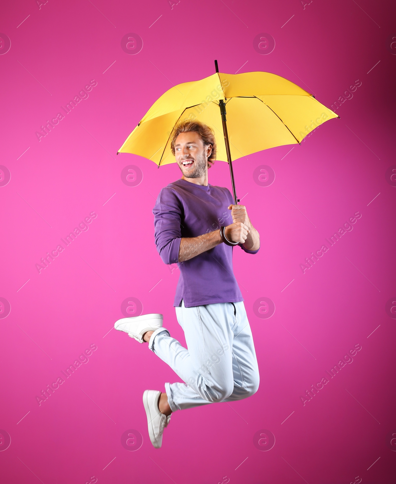 Photo of Man with yellow umbrella near color wall