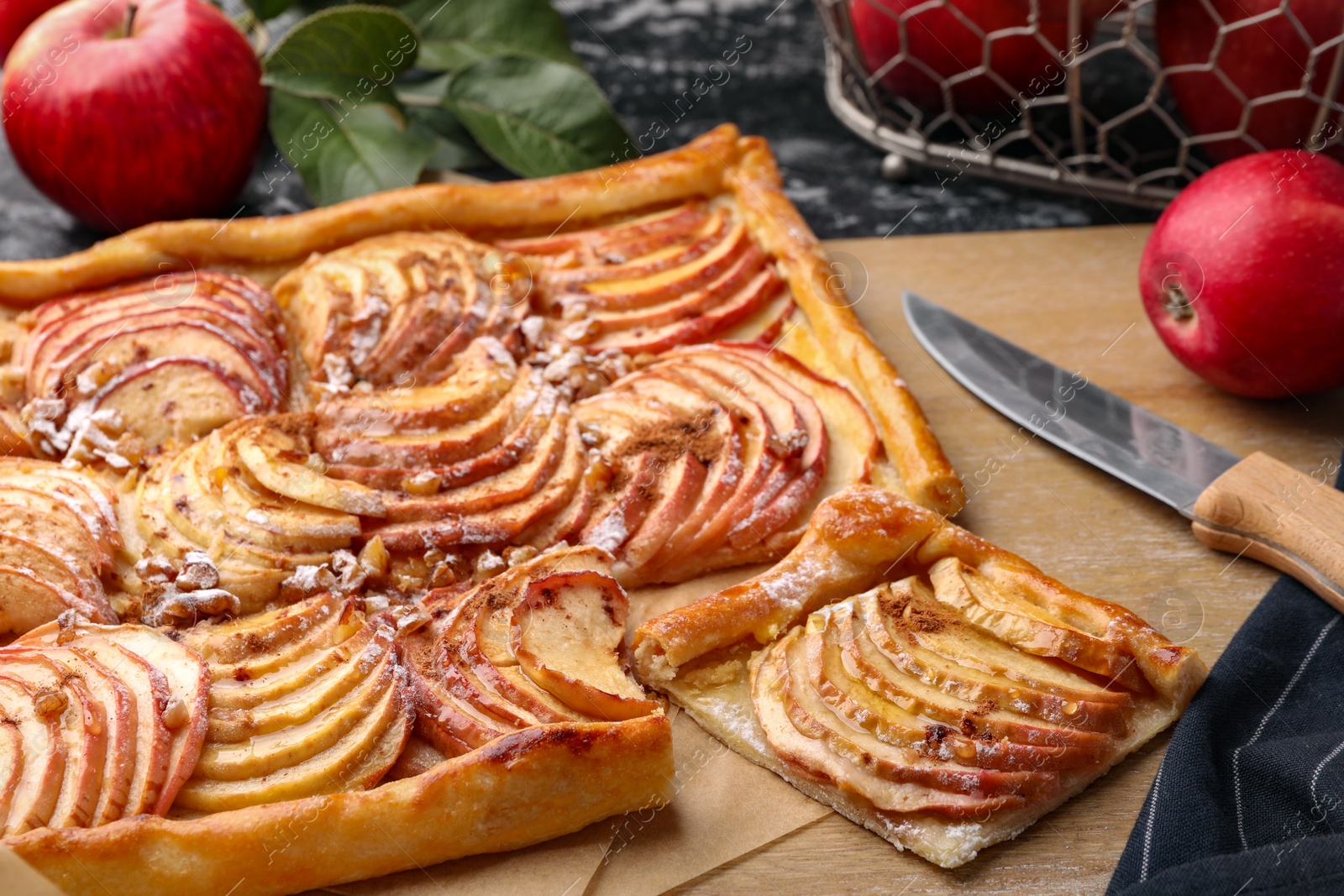 Photo of Tasty apple pie, knife and fresh fruits on table, closeup