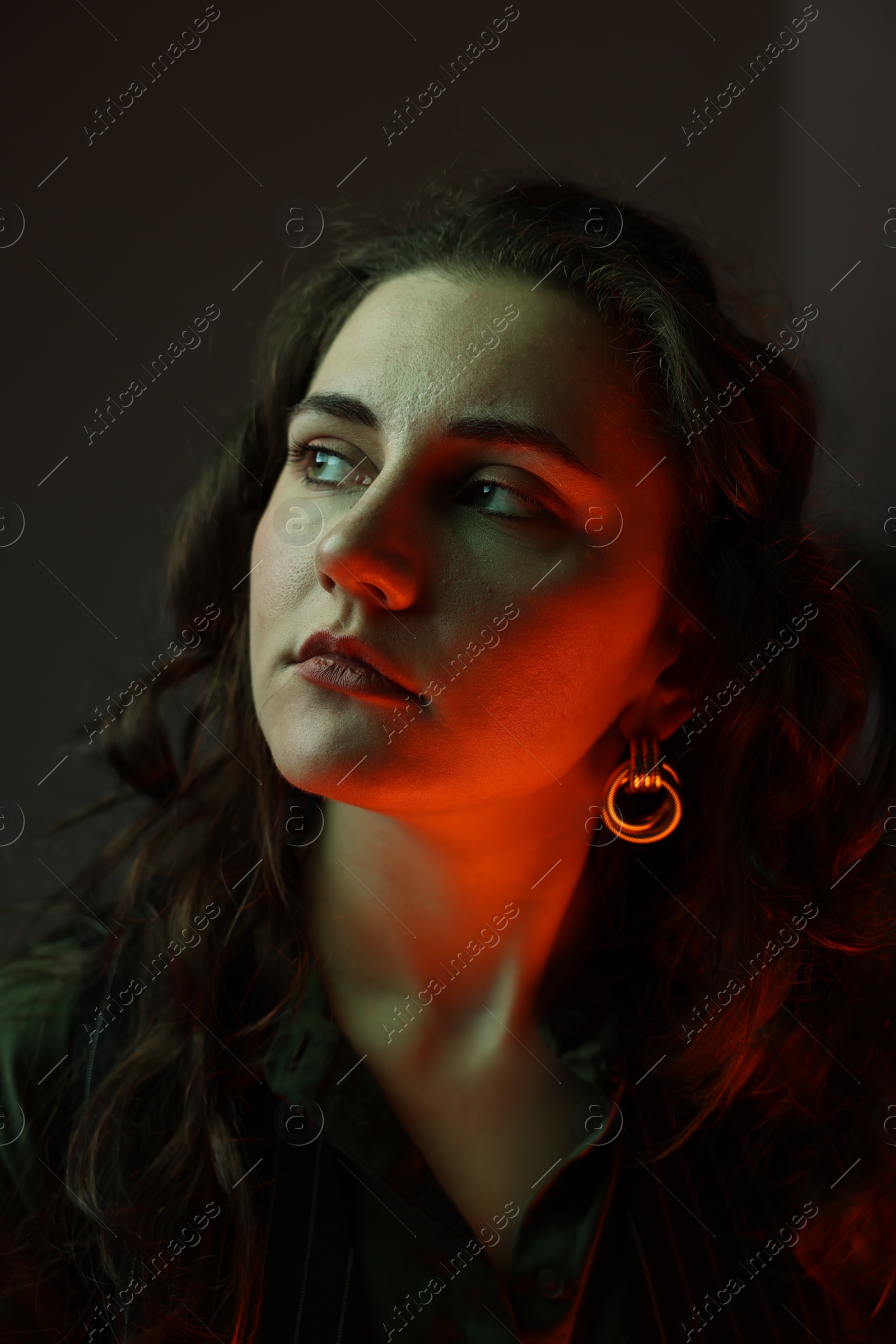 Photo of Portrait of beautiful young woman on dark background with neon lights, closeup