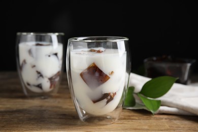 Photo of Glasses of milk with delicious grass jelly on wooden table