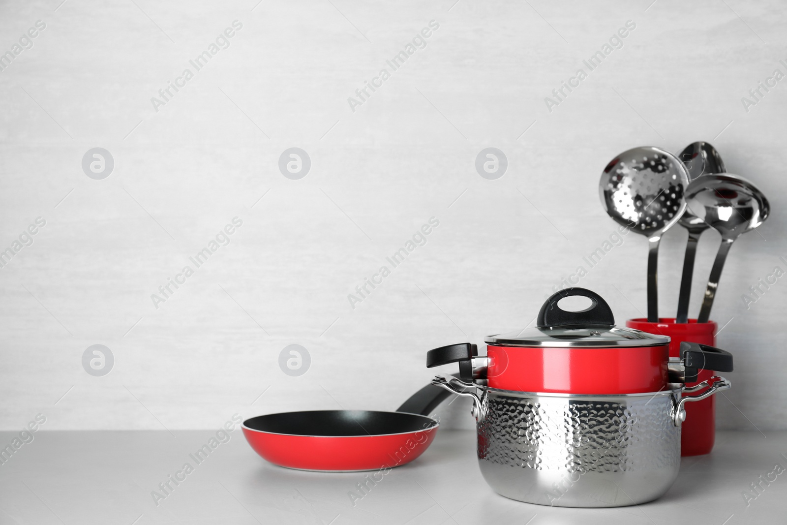 Photo of Set of clean cookware and utensils on table against light background. Space for text