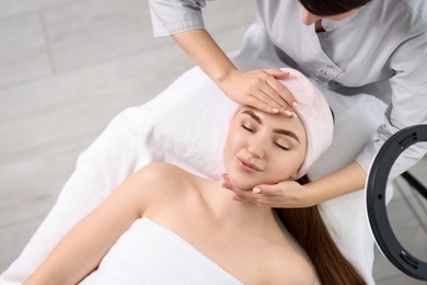 Cosmetologist making face massage to client in clinic, top view