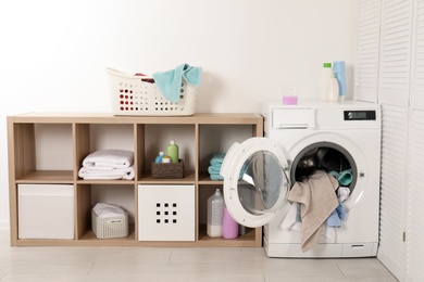 Photo of Washing machine with dirty towels in laundry room