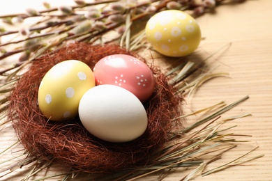 Photo of Sisal nest with painted Easter eggs on wooden table. Space for text