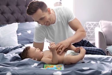 Photo of Young father with his cute little son on bed