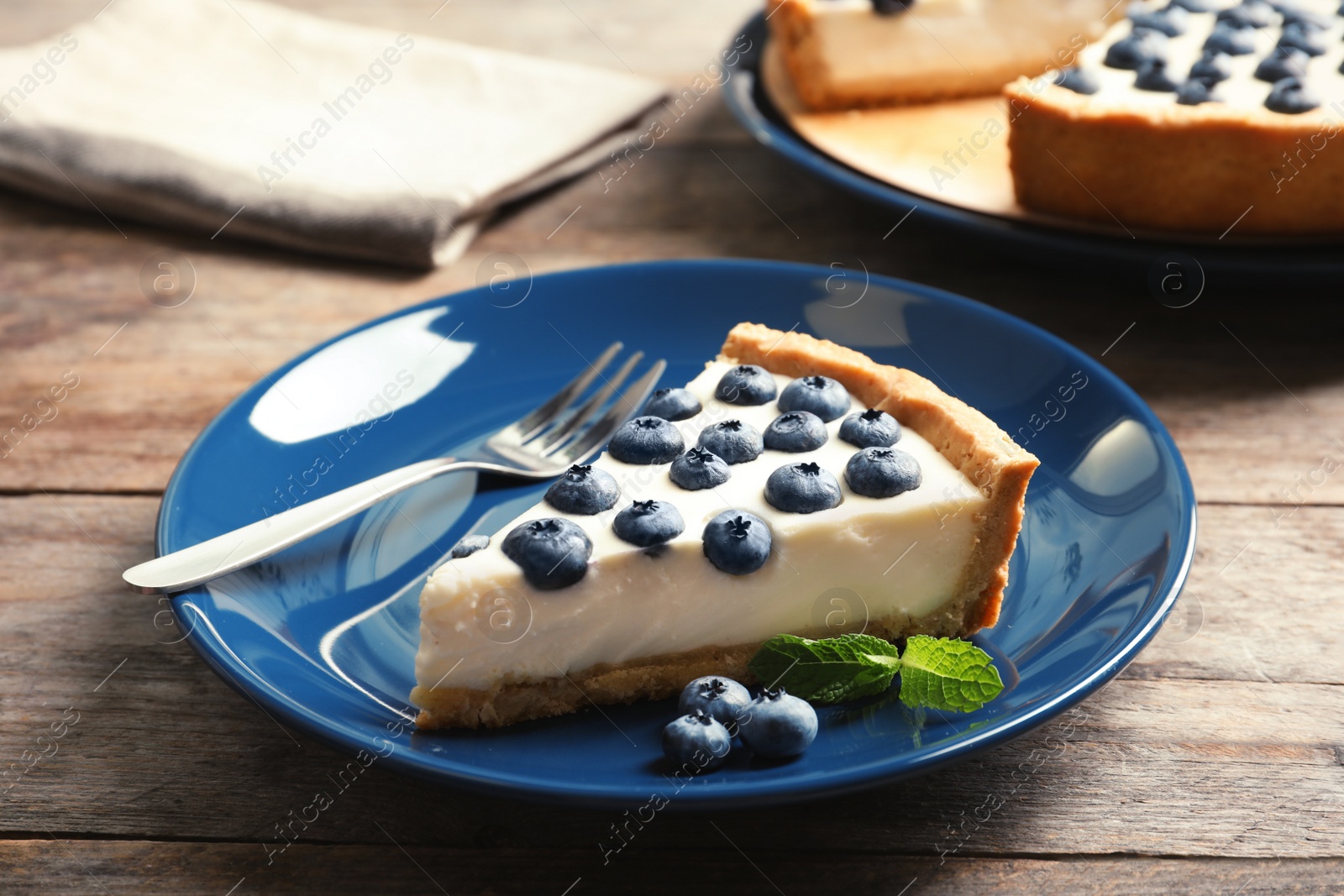 Photo of Plate with piece of tasty blueberry cake on table