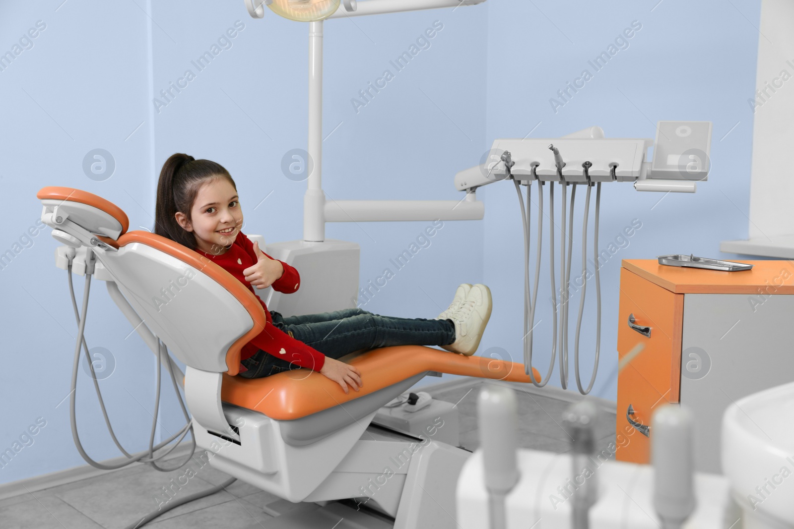 Photo of Happy little patient on dentist's chair in modern clinic
