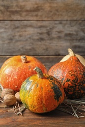 Photo of Different pumpkins on table against wooden wall. Autumn holidays