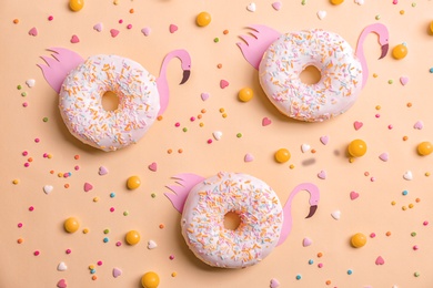 Photo of Fresh tasty donuts, candies and sprinkles on color background