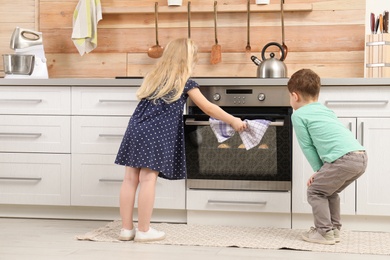 Photo of Cute children baking cookies in oven at home