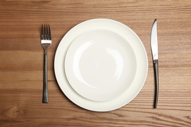 Photo of Empty dishware and cutlery on wooden background, top view. Table setting