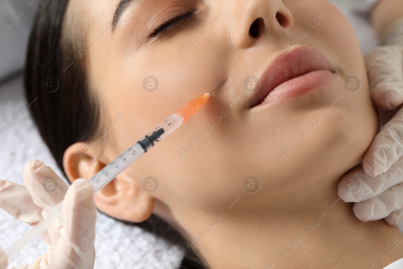 Photo of Doctor giving facial injection to young woman in clinic, closeup. Cosmetic surgery