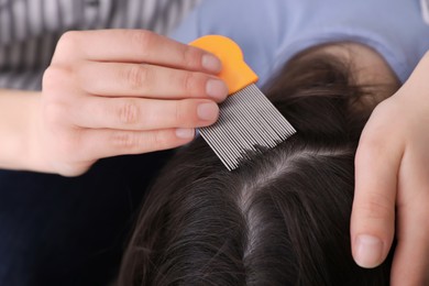 Photo of Mother using nit comb on her daughter's hair indoors. Anti lice treatment