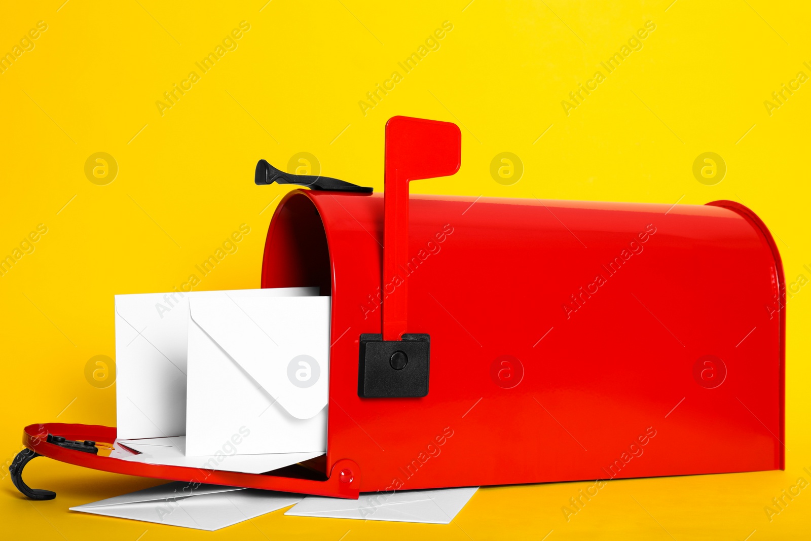 Photo of Open red letter box with envelopes on yellow background, closeup