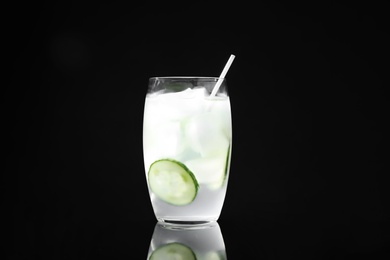 Glass of delicious cucumber martini with ice on dark background