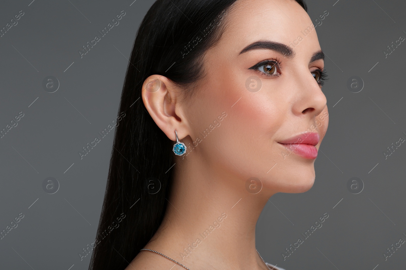 Photo of Beautiful young woman with elegant earrings on dark grey background, closeup