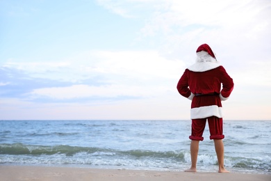 Santa Claus on beach, space for text. Christmas vacation