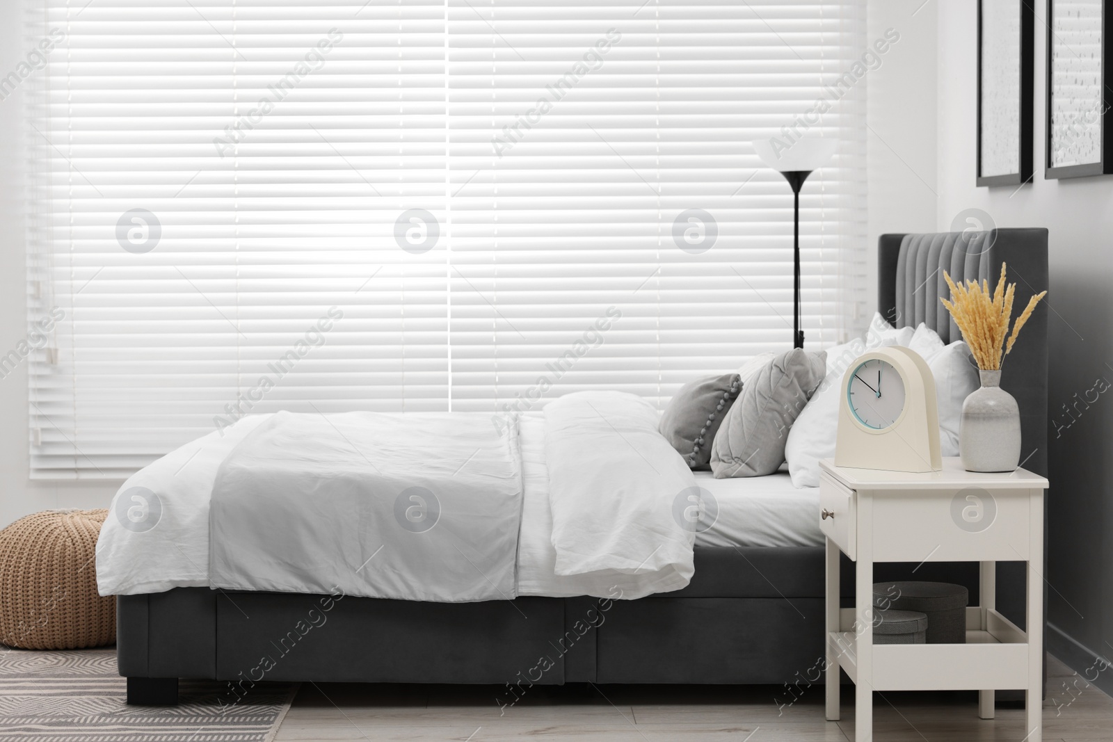 Photo of Stylish bedroom interior with large bed, bedside table and lamp