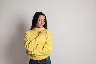 Photo of Beautiful young woman wearing yellow warm sweater on white background. Space for text