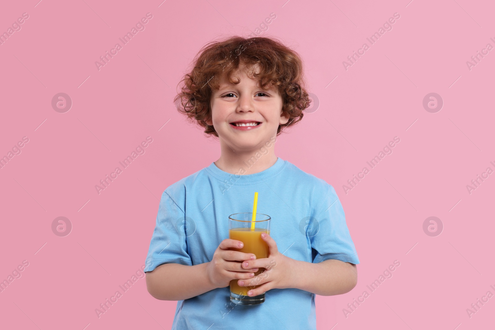 Photo of Cute little boy with glass of fresh juice on pink background