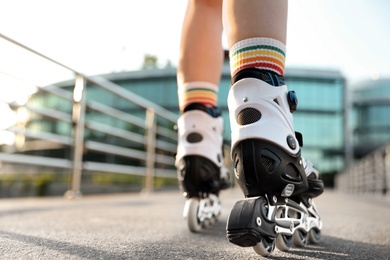 Photo of Young woman with roller skates outdoors, closeup. Space for text