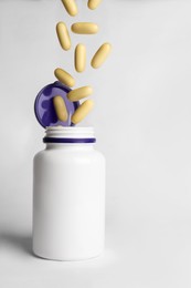 Photo of Pills falling into medical bottle on white background