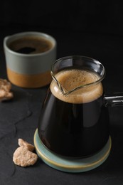 Photo of Turkish coffee. Glass cezve, cup and sugar on dark grey table