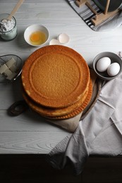 Photo of Delicious homemade sponge cake and ingredients on white wooden table, above view