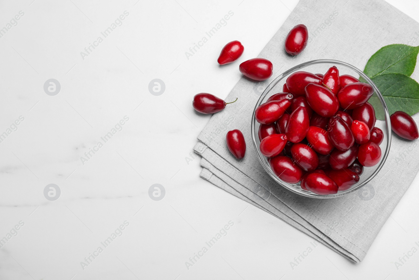 Photo of Fresh ripe dogwood berries on white marble table, flat lay. Space for text